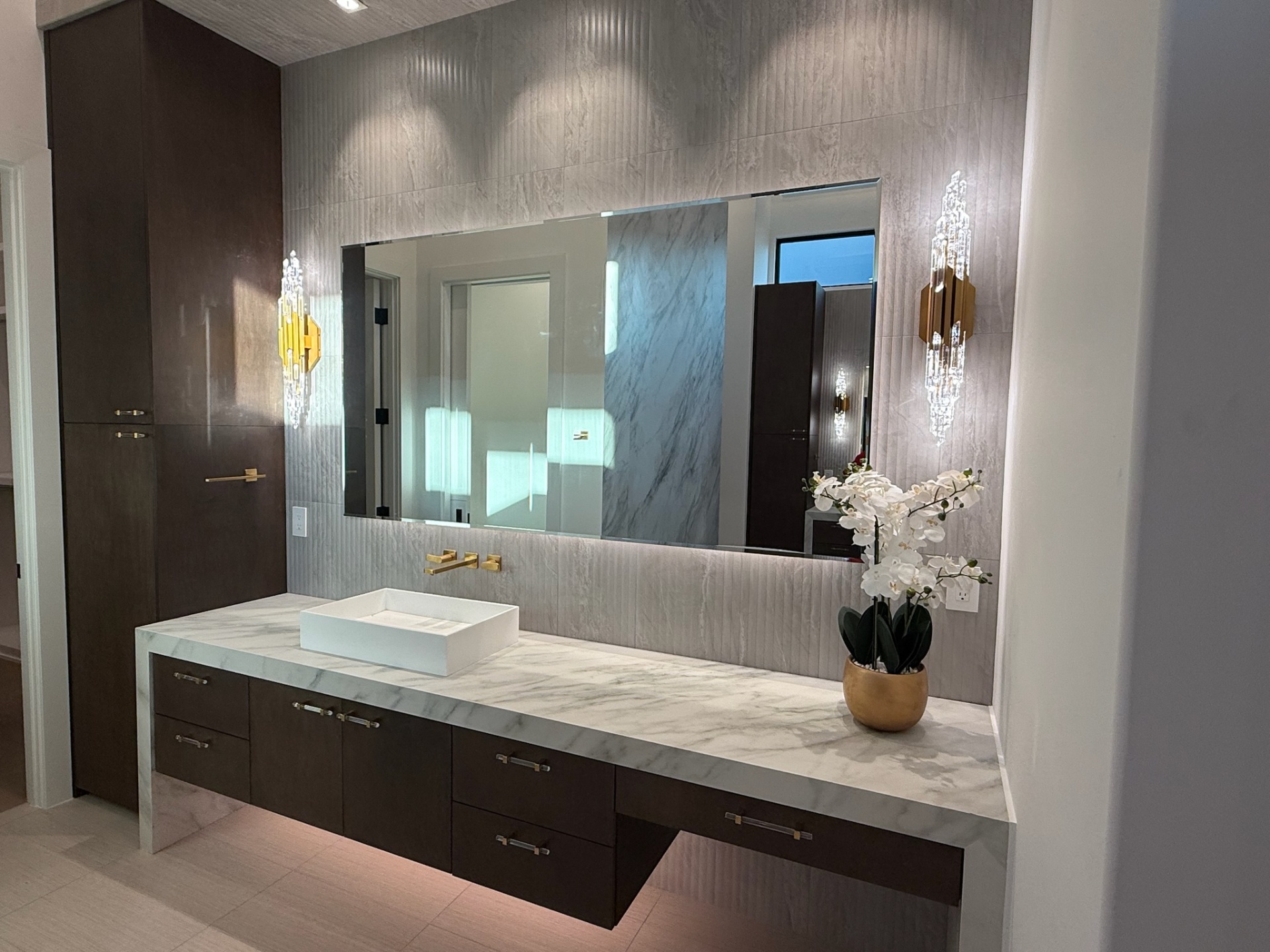 Primary bath vanity with floating espresso oak cabinetry and crystal sconces by Amaya