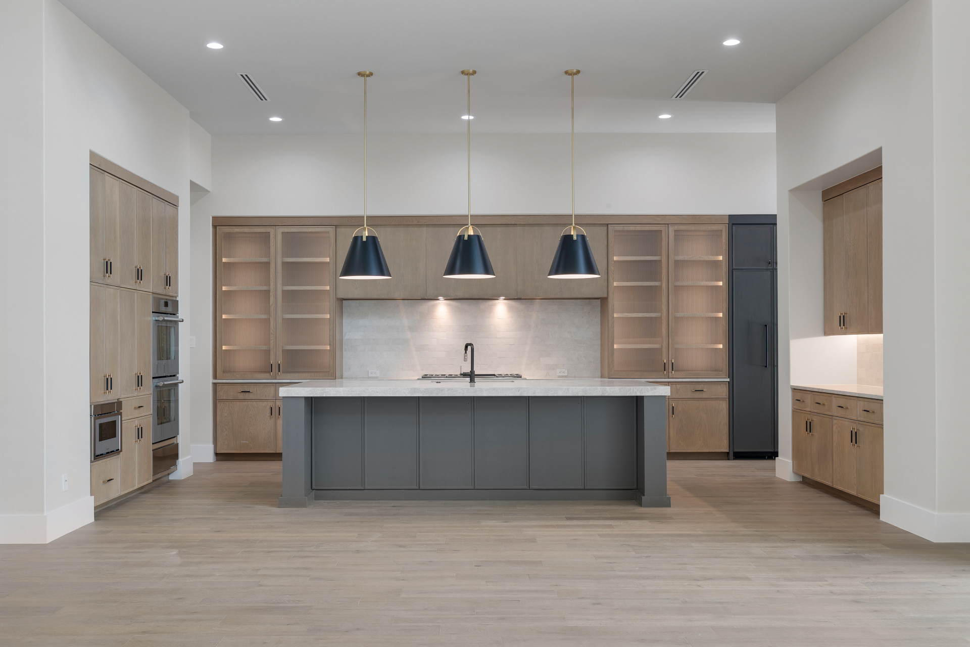 White oak kitchen with fluted glass display cabinets and graphite island in The Dominion by Amaya