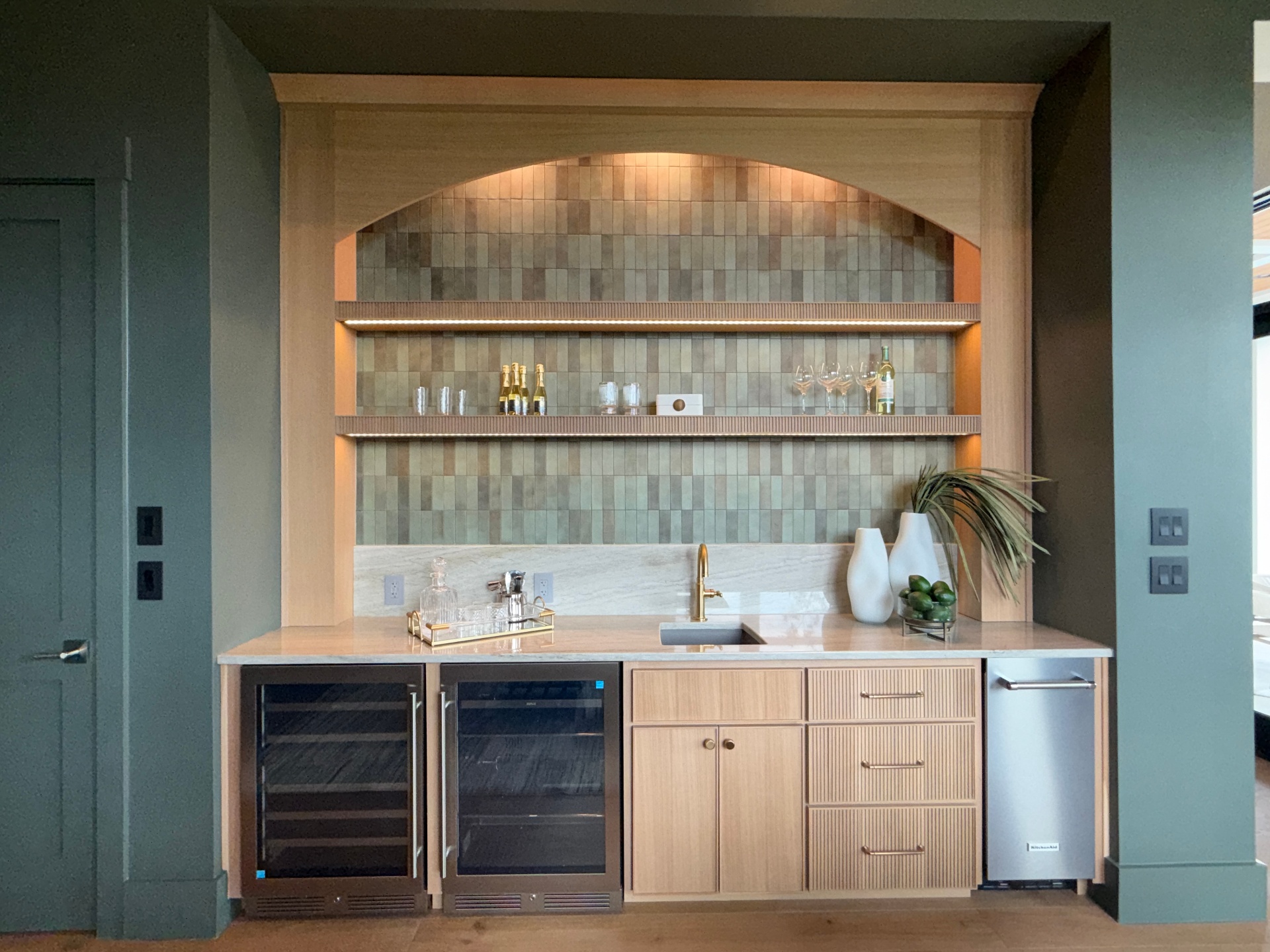 Arched wet bar with fluted white oak base cabinetry and green zellige tile back by Amaya