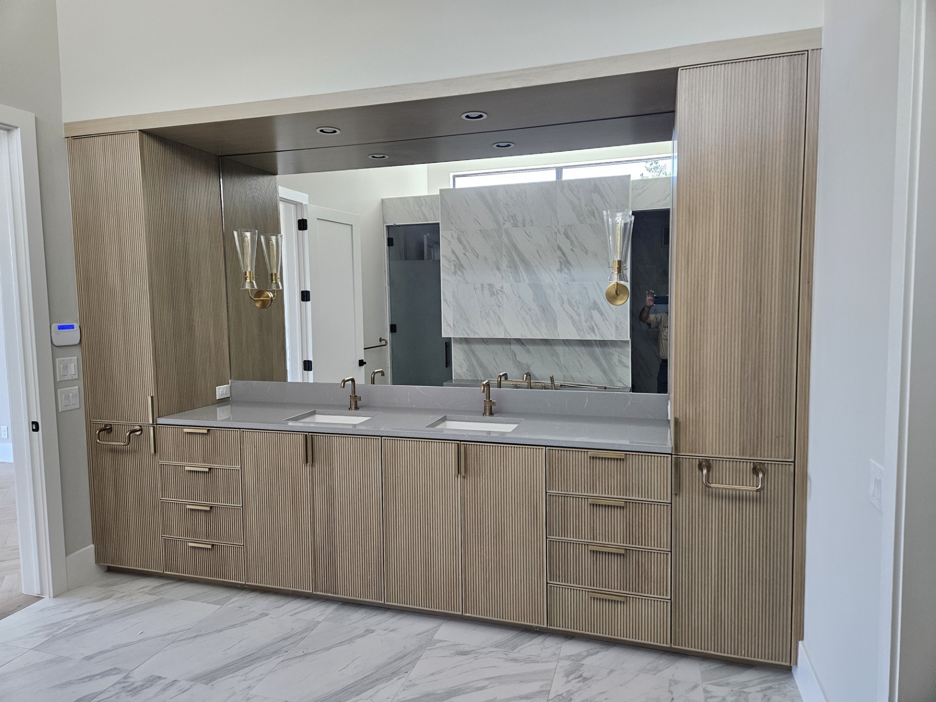 Modern master bath with fluted white oak dual vanity, quartz counters, and brass hardware by Amaya