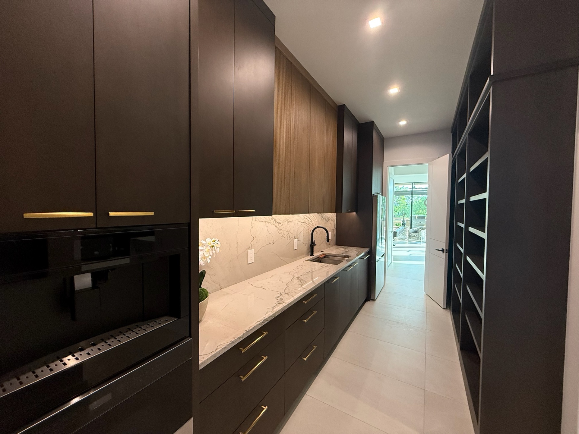 Espresso oak butler's pantry with fluted upper cabinetry and brass pulls by Amaya