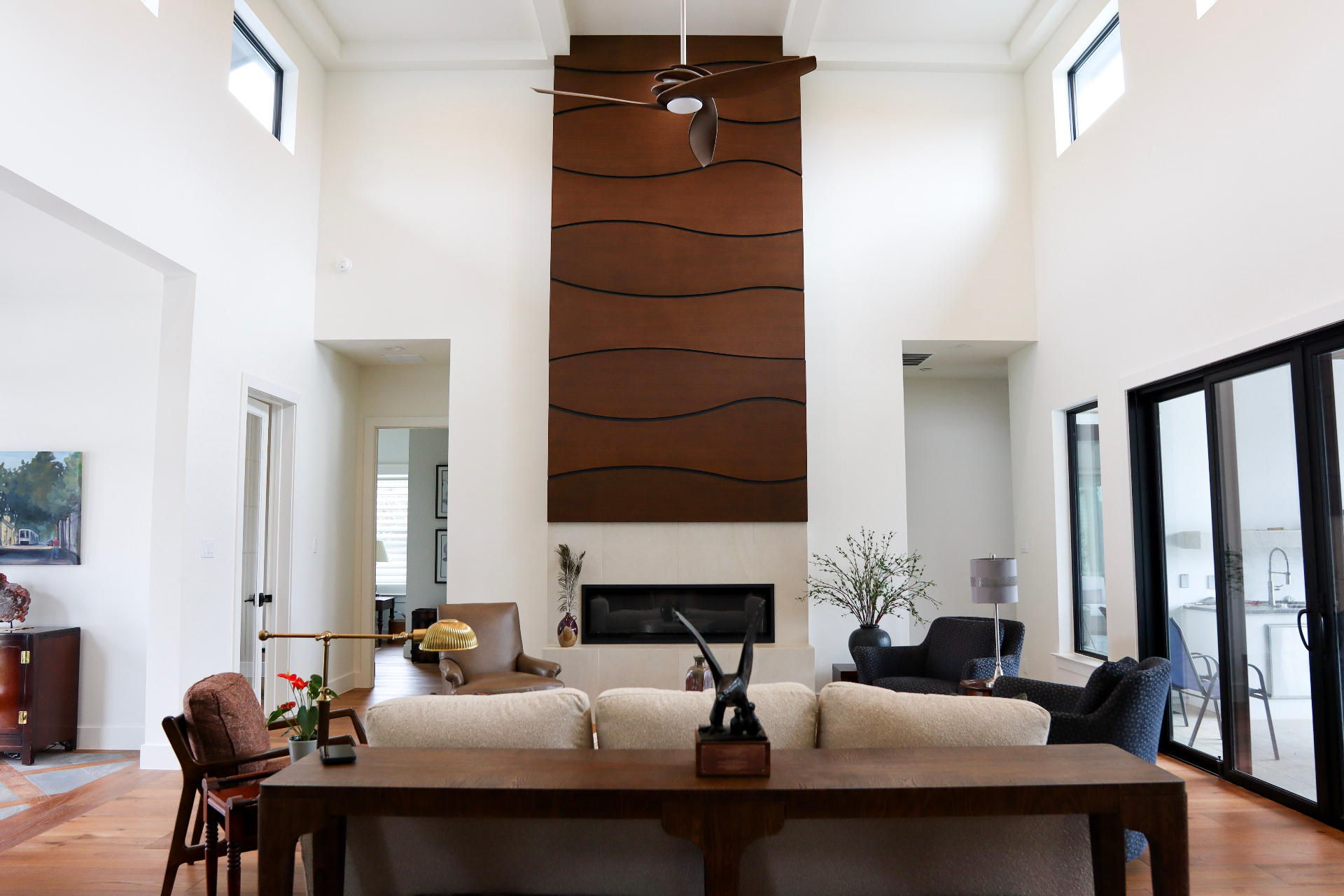 Great room with a two-story custom rift-sawn white oak fireplace surround featuring sculpted wave-panel millwork by Amaya